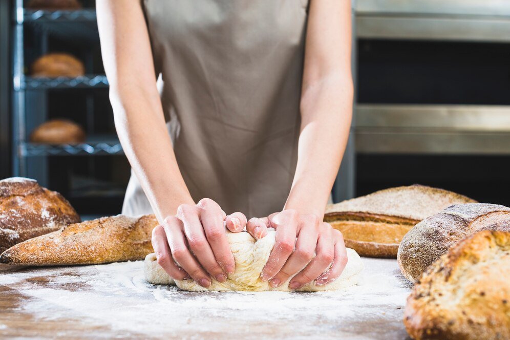 close-up-female-baker-kneading-dough-with-flour-wooden-surface_23-2148189071